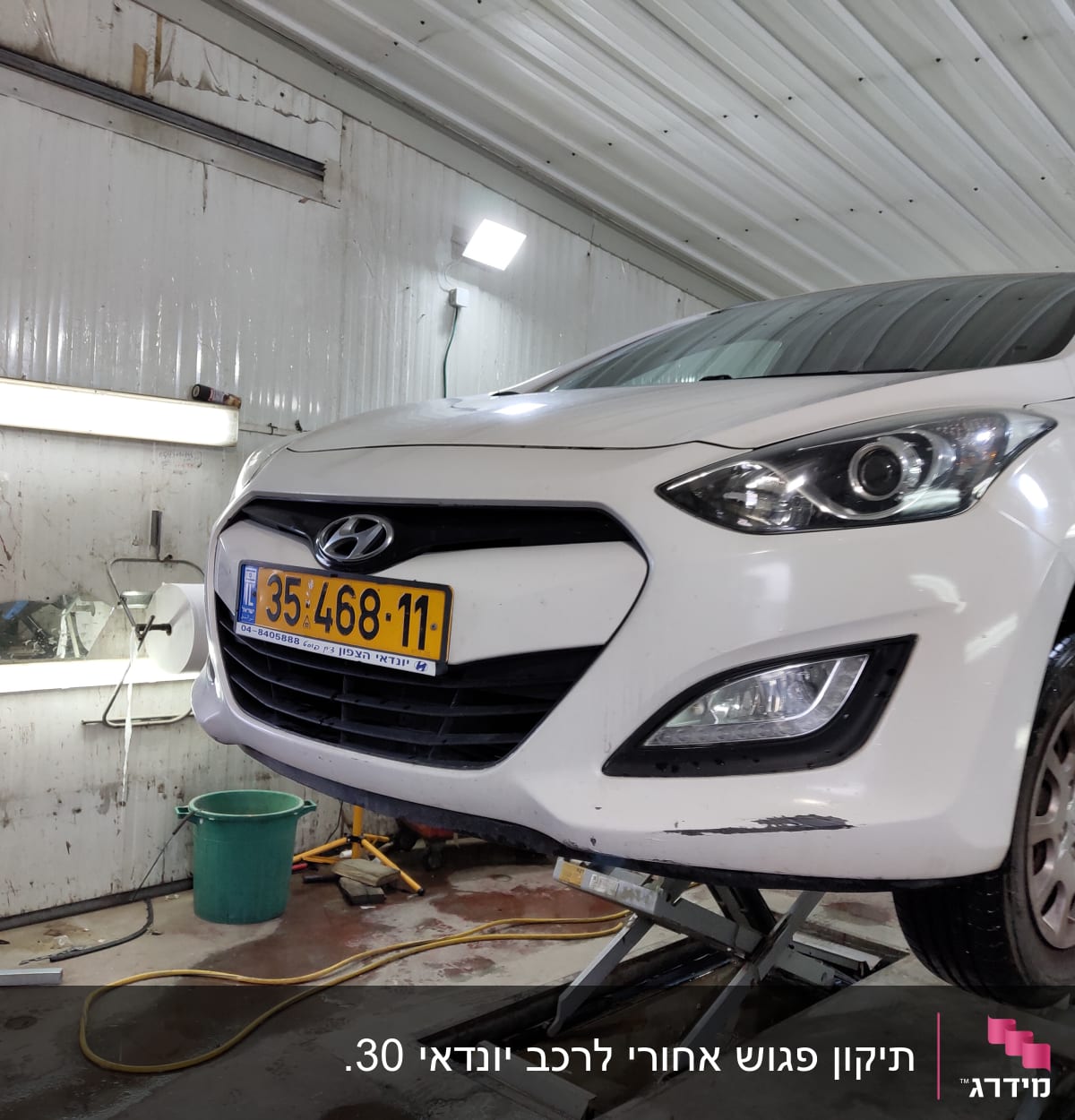 רכב לבן על מעלית במוסך עם כלים מסביב